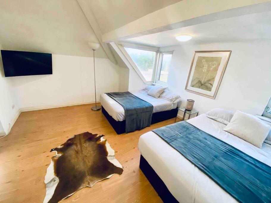 伦敦Penthouse studio with 2 double beds & smart TV. Great London Location的卧室配有两张床,地面上有一棵树 ⁇ 