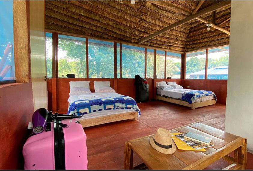 伊基托斯Ceiba Amazon Lodge的一间设有两张床和一张带行李箱的桌子的房间