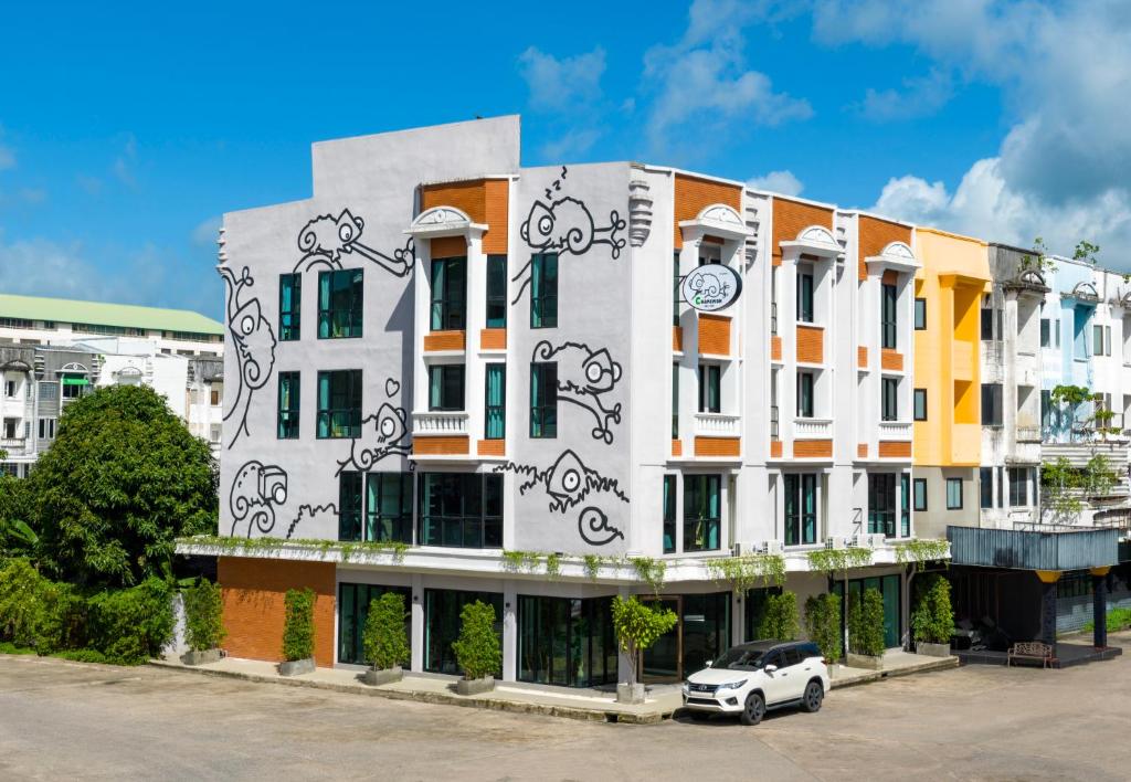 普吉镇Chamemon Bed Phuket Town的前面有停车位的建筑