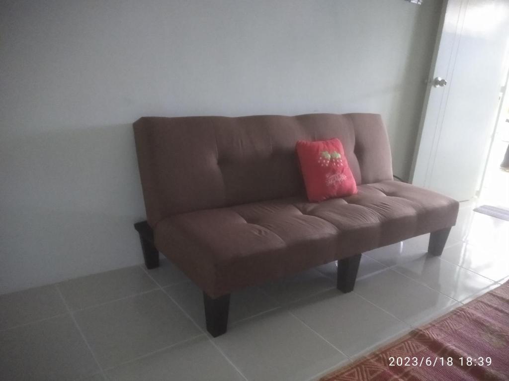 LunasRumah Lunas的一张棕色的沙发,上面有粉红色的枕头
