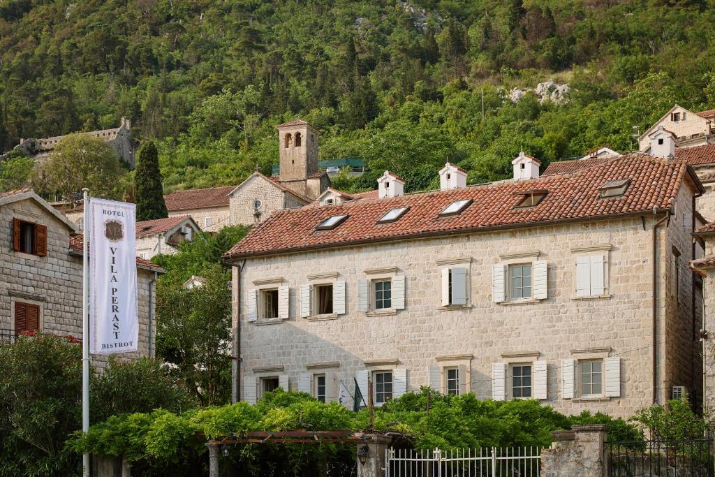 帕里斯特Vila Perast Boutique Hotel的一座大石头建筑,背景是一座山