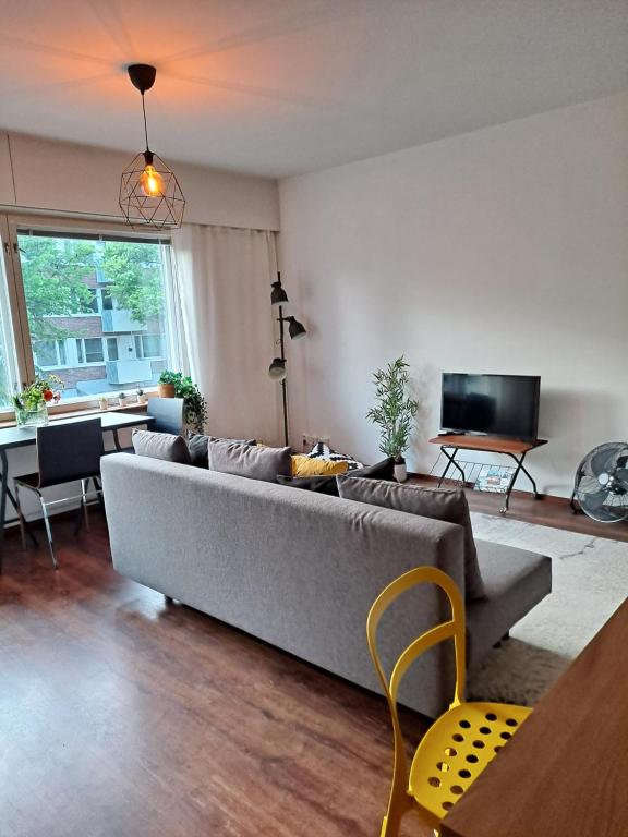赫尔辛基Puotilan idylli meren lähellä的客厅配有灰色的沙发和桌子