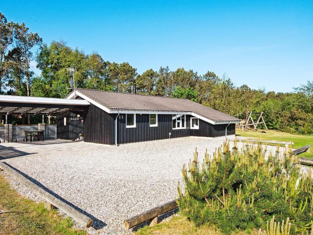 Nørby8 person holiday home in Ringk bing的前面有砂石车道的黑色建筑