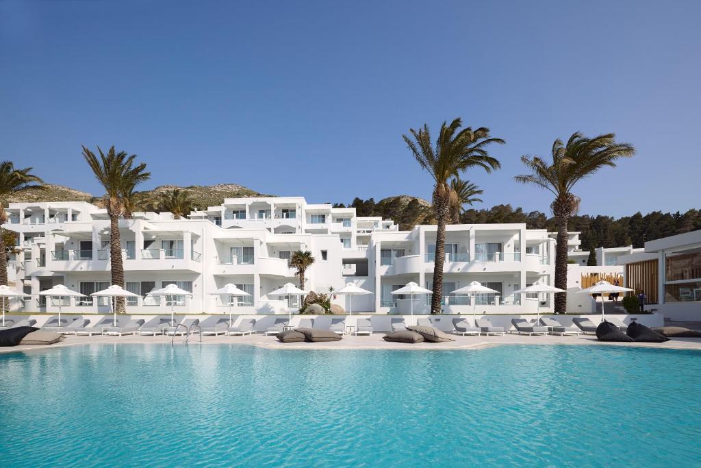 Ágios FokásDimitra Beach Hotel & Suites的一座种植了棕榈树和游泳池的大型白色建筑