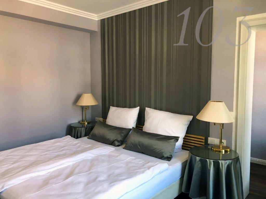 巴特皮尔蒙特Rein Klassik Hotel的一间卧室配有一张床和两张带台灯的桌子。