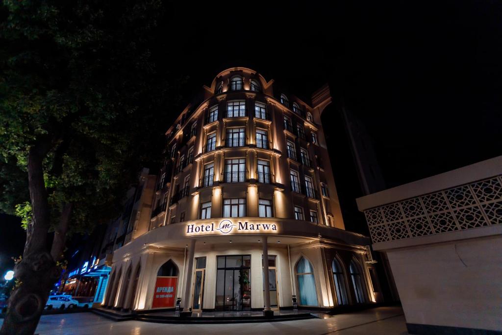塔什干Hotel Marwa Tashkent Pool&Spa的一座有灯的建筑,晚上有标志