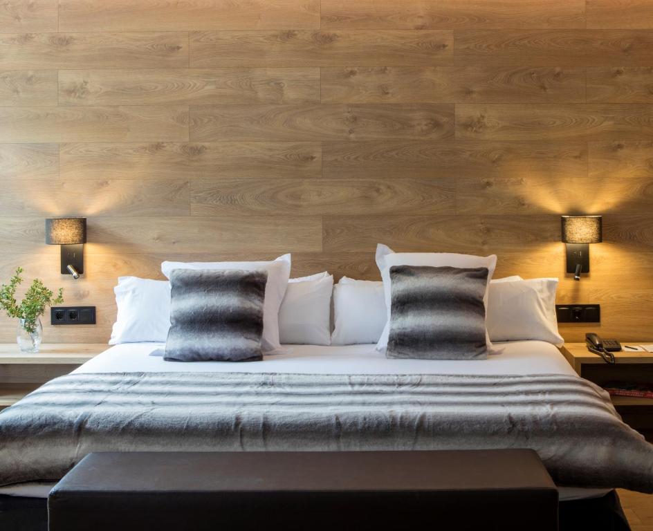 安道尔城阿克塔艺术酒店的一间卧室配有一张带木墙的大床