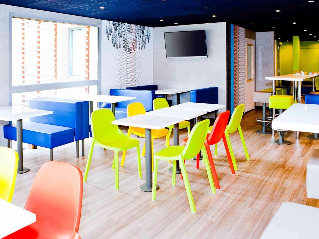 梅斯梅兹中心宜必思快捷酒店的用餐室配有桌子和五颜六色的椅子