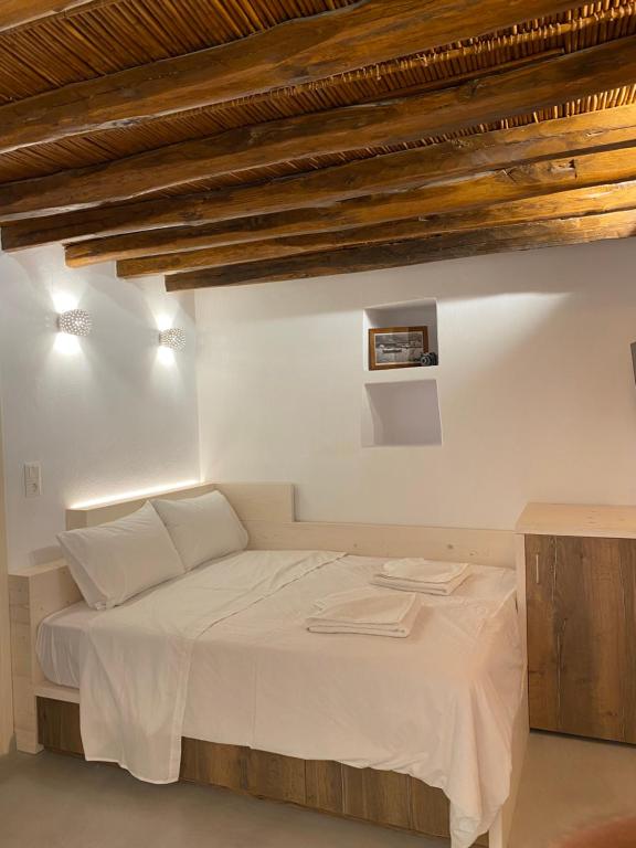 KóstosCozy apartment Kostos的一间卧室配有白色床单和木制天花板。