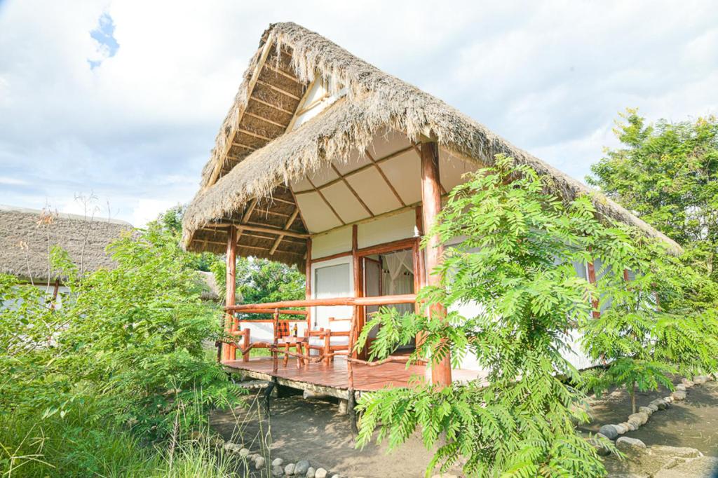 卡塞斯Kazinga Wilderness Safari Camp的茅草屋顶的房屋,带甲板