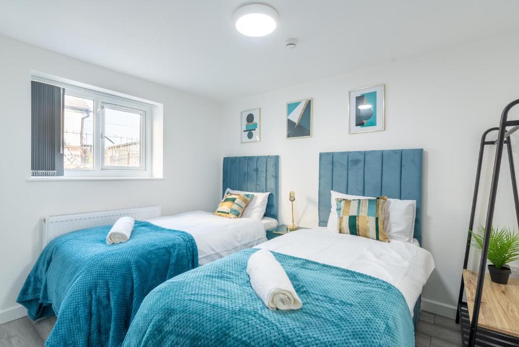 卡迪夫Exquisite Cardiff Apartments- with Garden Lounge & Games Room的蓝色和白色的客房内的两张床