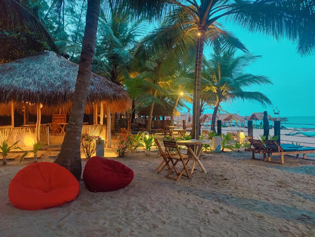 阿鲁甘湾Atteriya CHILL的棕榈树海滩,沙滩上摆放着桌椅
