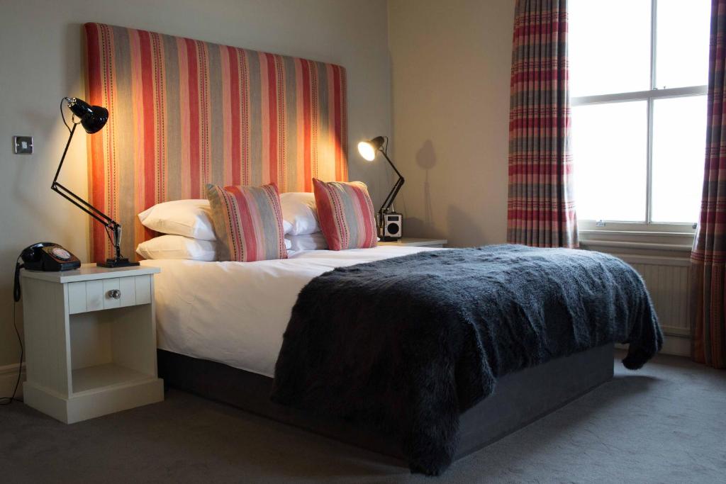 哈里奇码头酒店的一间卧室配有一张床铺,床上有毯子