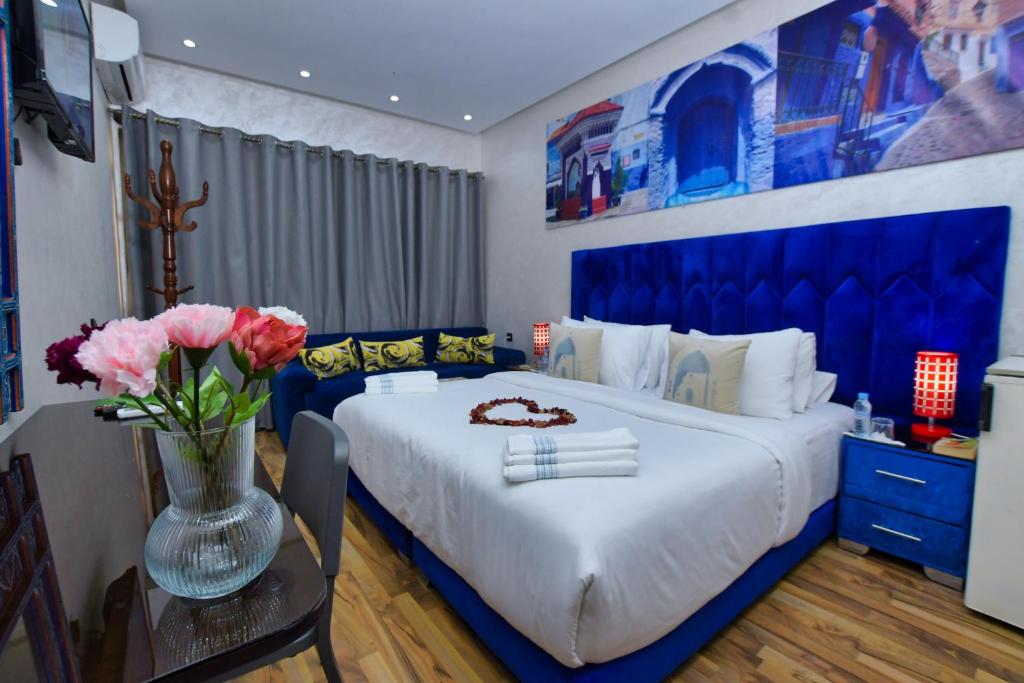 舍夫沙万Hotel Dar Annasr的蓝色和白色的卧室,配有一张床和花瓶