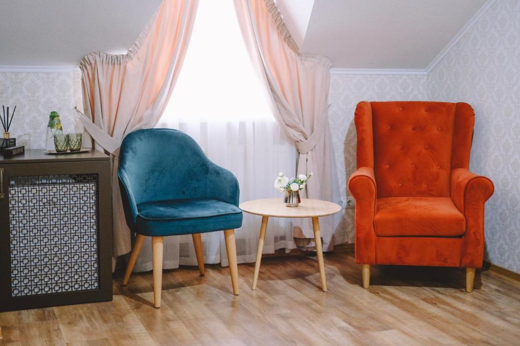 文尼察Hotel DENINNA的客厅配有两把椅子和一张桌子