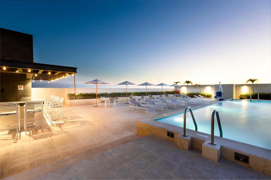 梅里达Residence Inn by Marriott Merida的一个带桌椅和遮阳伞的游泳池