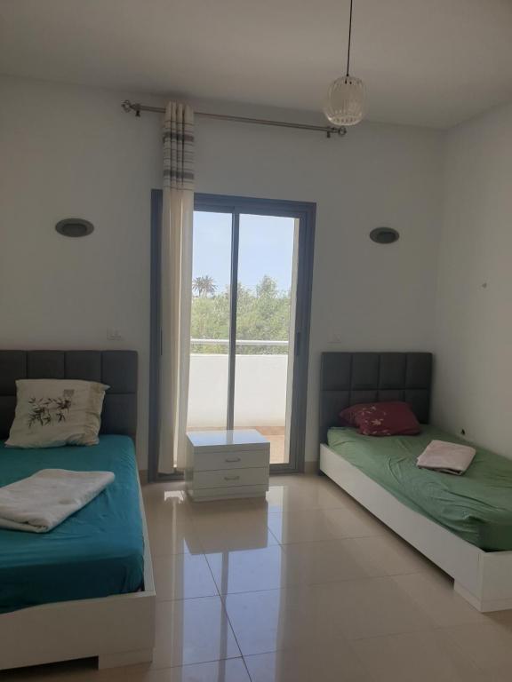 Awlād ‘UmarVilla Château D'eau Djerba的白色客房的两张床,设有窗户
