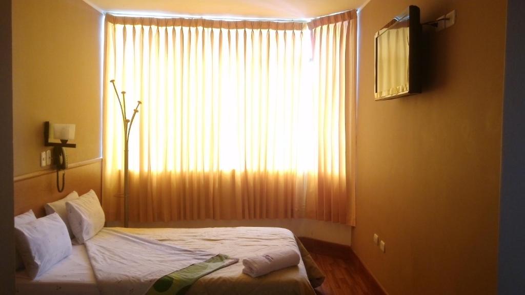 齐克拉约Hospedaje Oasis的卧室在窗户前配有一张床