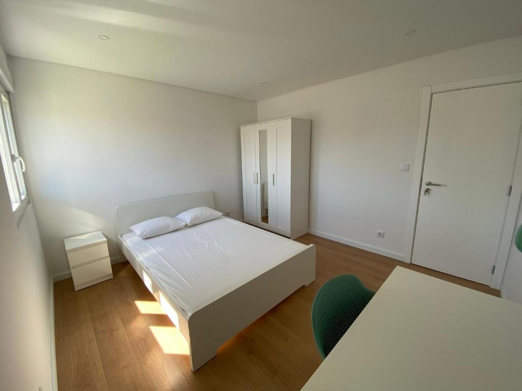 奥埃拉斯Carcavelos Beach Walking distance room的白色卧室配有床和椅子