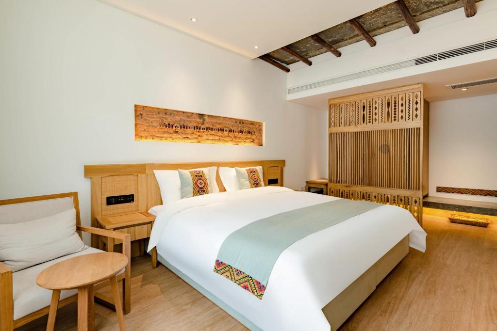 张家界Yoba Boutique Hotel的卧室里有一张白色的大床和一把椅子