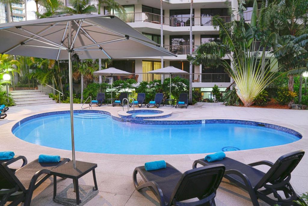 黄金海岸创世纪公寓酒店的一个带躺椅和遮阳伞的游泳池