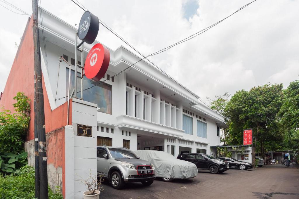茂物RedDoorz Syariah near Taman Air Mancur Bogor的前面有汽车停放的建筑