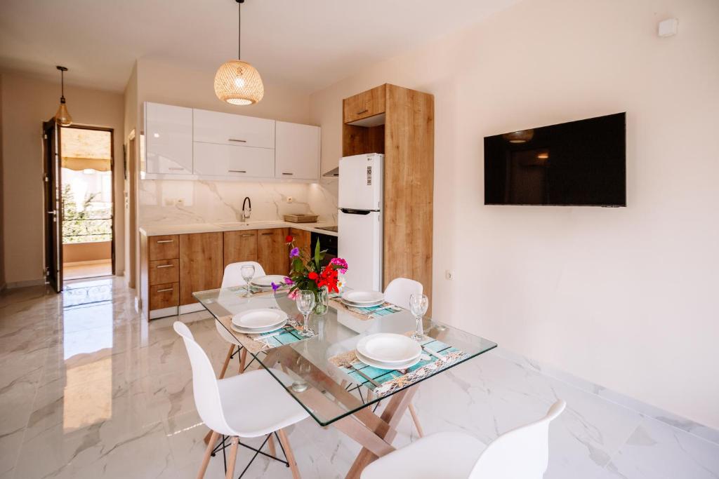 卡拉马孔Nadia Apartments B的厨房配有玻璃桌和白色椅子
