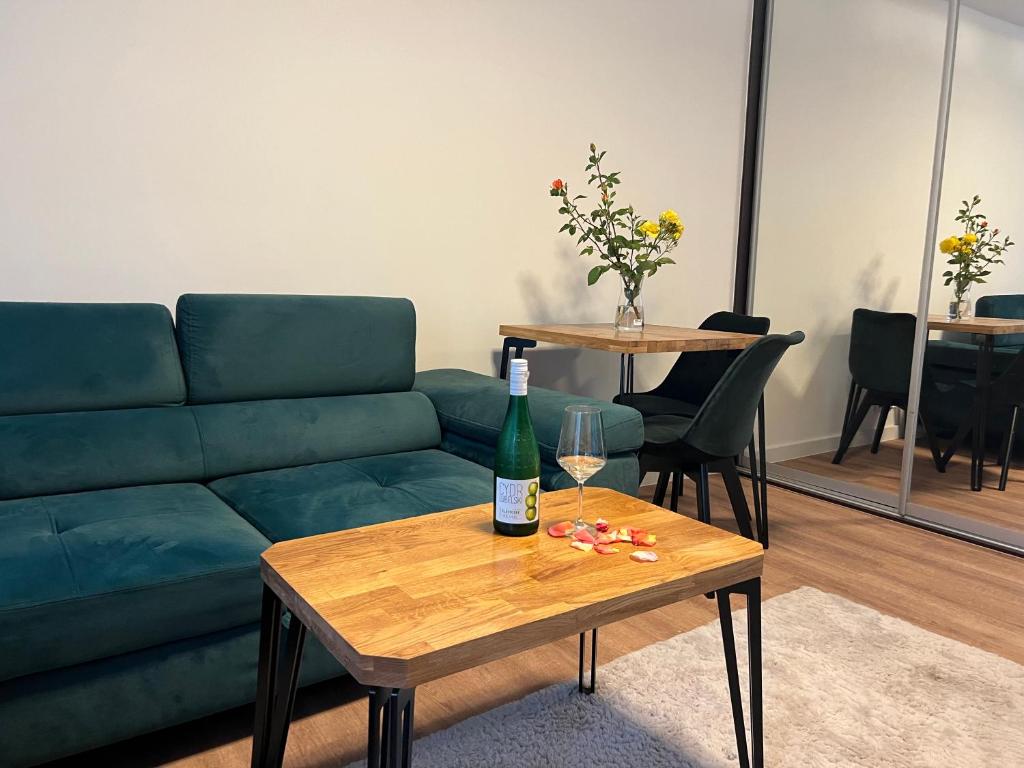 弗罗茨瓦夫Last Pub Rynek-Klima-ParkigFree-Netflix-YouTube的客厅配有绿色沙发和桌子上的一瓶葡萄酒