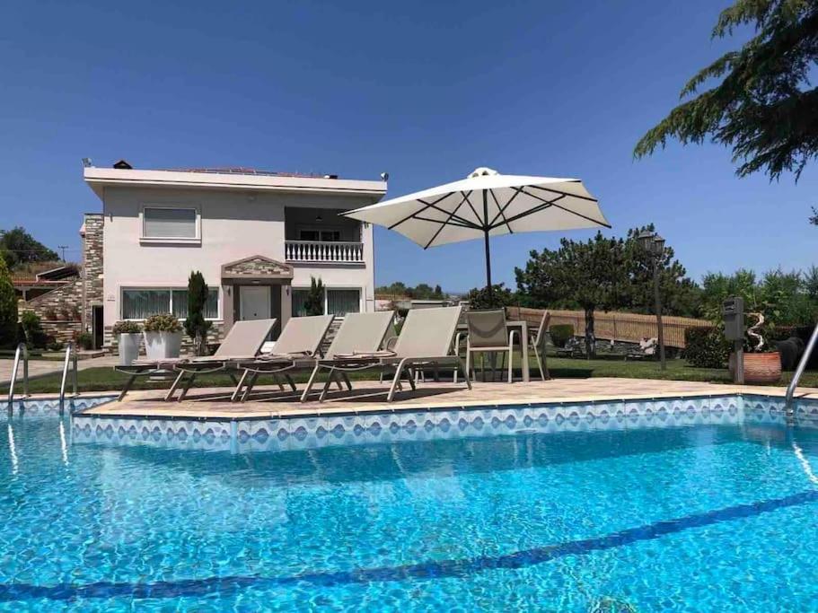普拉奇里奥Villa Casa Chrissy的房屋旁的游泳池配有椅子和遮阳伞