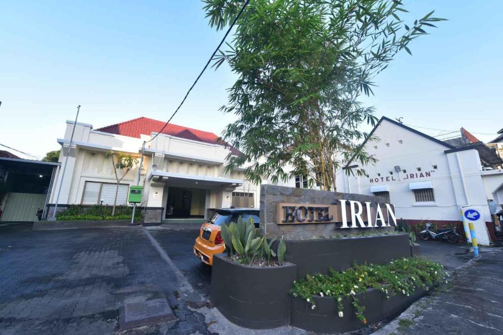 泗水Hotel Irian Surabaya的停在大楼前停车场的汽车