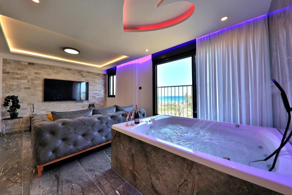 海法חלום מול הים - סוויטת נופש יוקרתית עם ג'קוזי ונוף לים的带沙发的客厅设有大浴缸