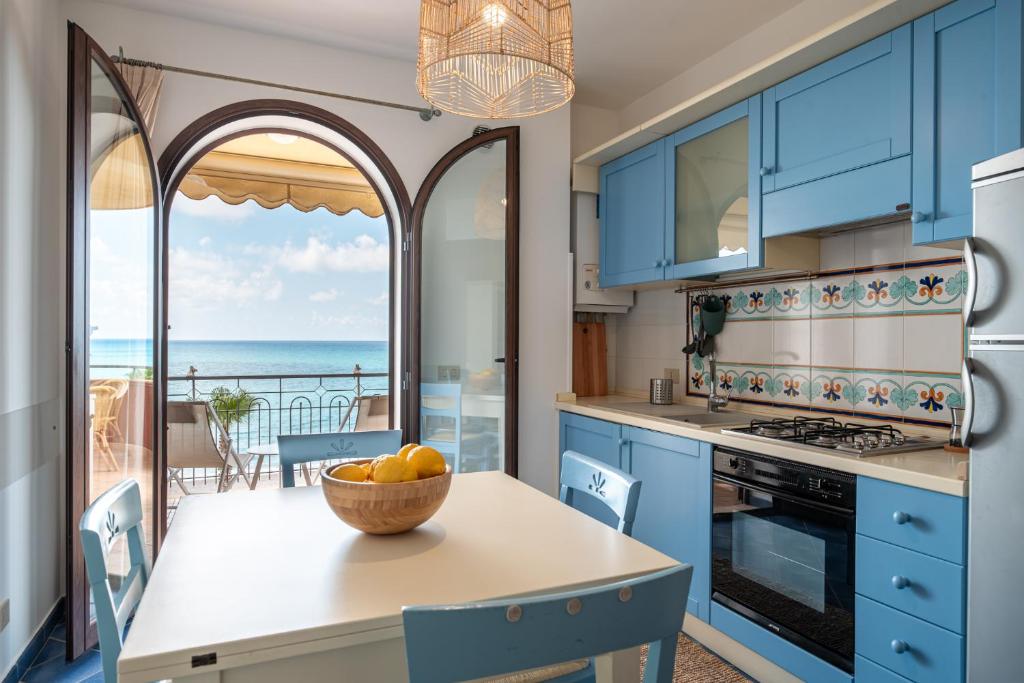 卡普多兰多Residence L'Arcipelago Appartamenti Fronte Mare con Ampio Balcone的厨房配有蓝色橱柜和一张带一碗水果的桌子