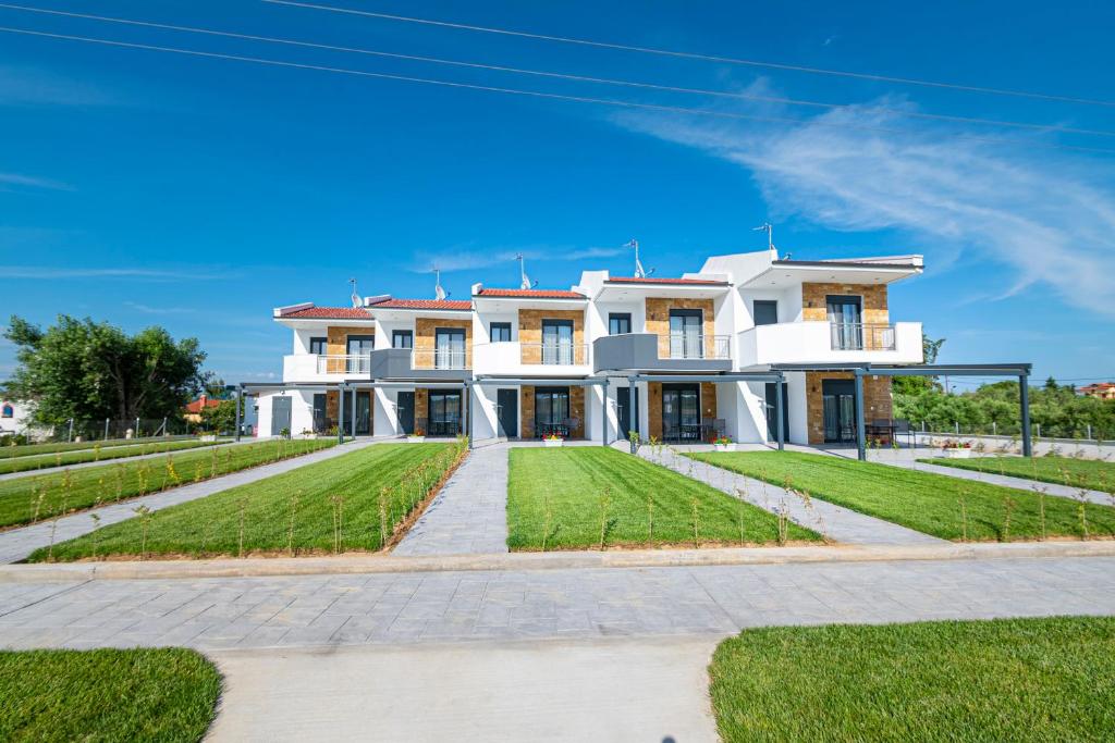 尼坡帝Chryssis Village by Travel Pro Services - Nea Potidaia Halkidiki的一座带绿色草坪的大型白色房屋