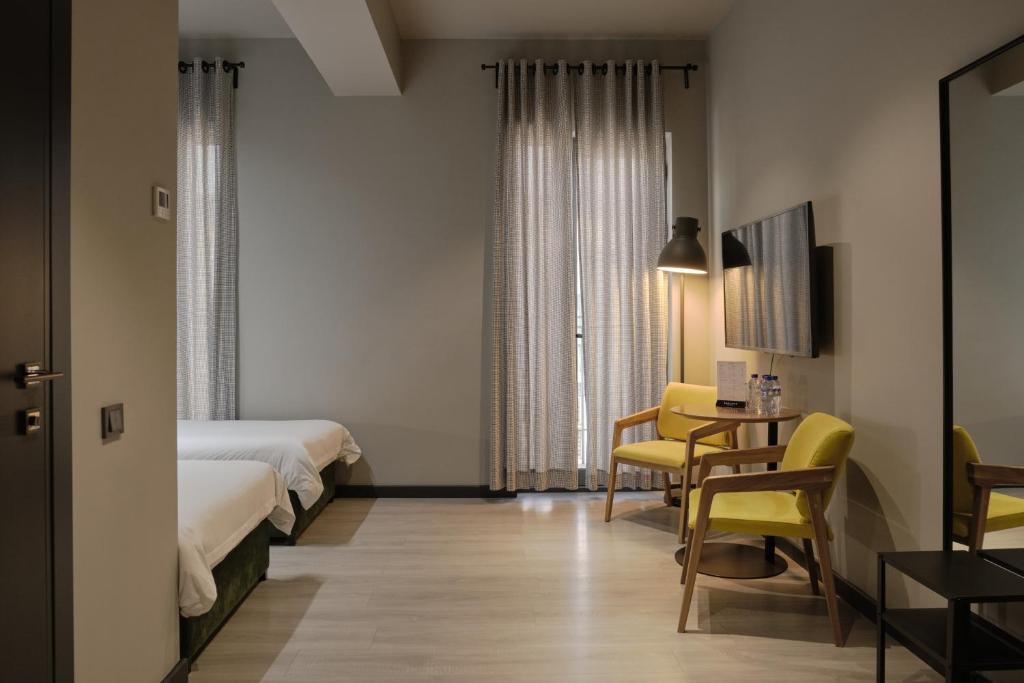 塔什干Sapiens Hotel的酒店客房带两张床和一张桌子以及椅子。