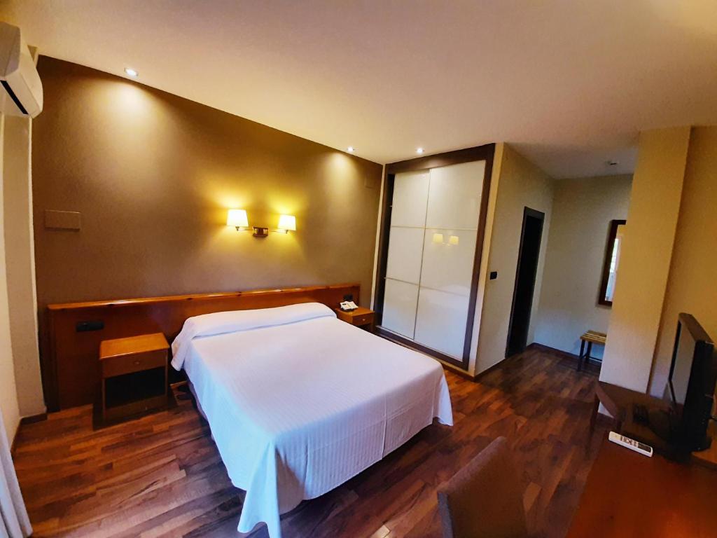 卡迪瓦维尼萨酒店的卧室配有白色的床和电视。