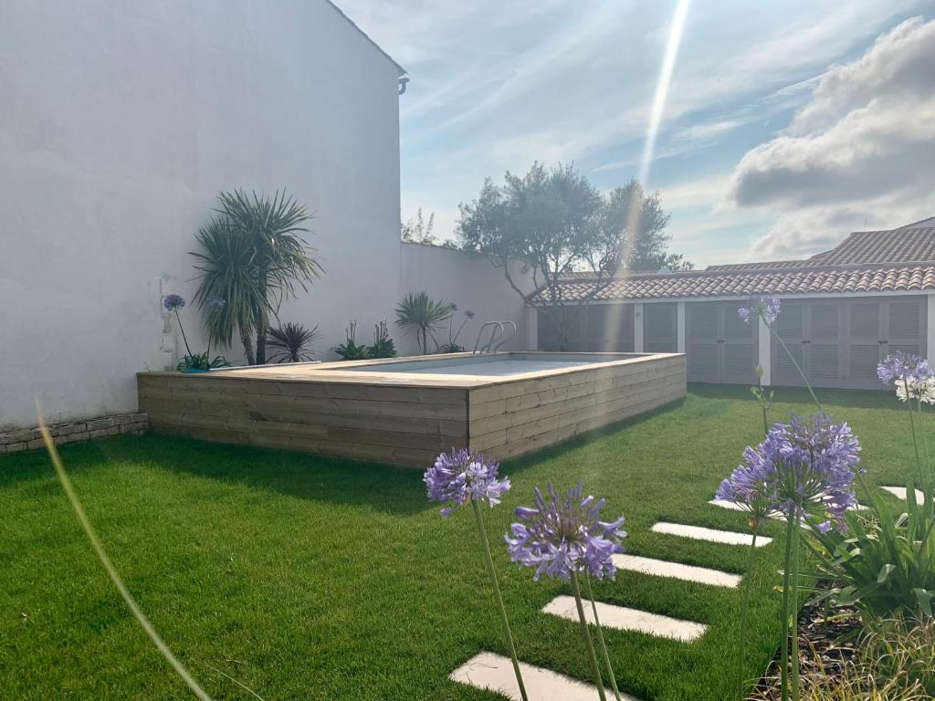 圣马丹德雷CAP O SUD grande maison avec Piscine à St Martin de Ré的一个带游泳池和紫色鲜花的后院