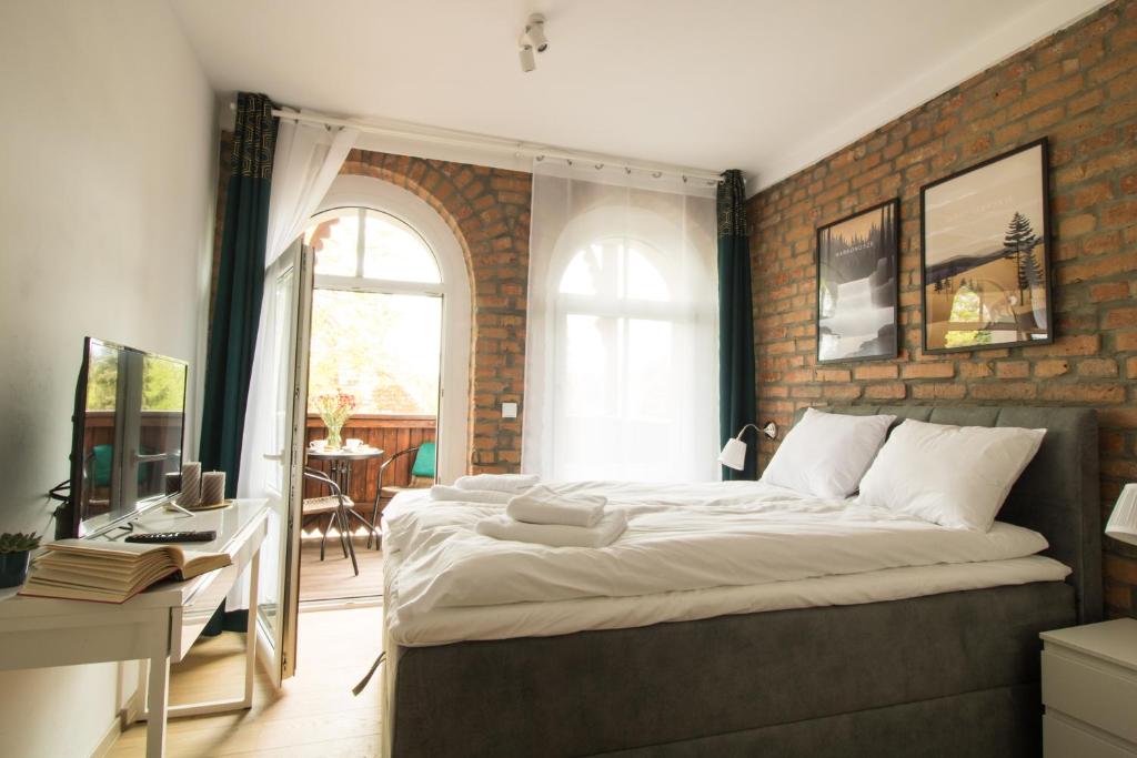 波兰尼卡-兹德鲁伊Apartamenty Dębowa 3的一间卧室设有一张大床和砖墙