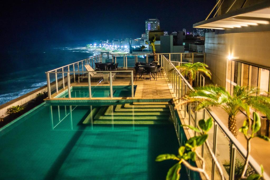 马卡埃Paradiso Macae Hotel的一座带游泳池的建筑的晚上阳台
