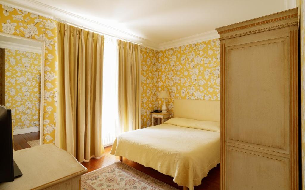 马尔戈Hôtel de Margaux的一间卧室配有一张黄色壁纸床和窗户