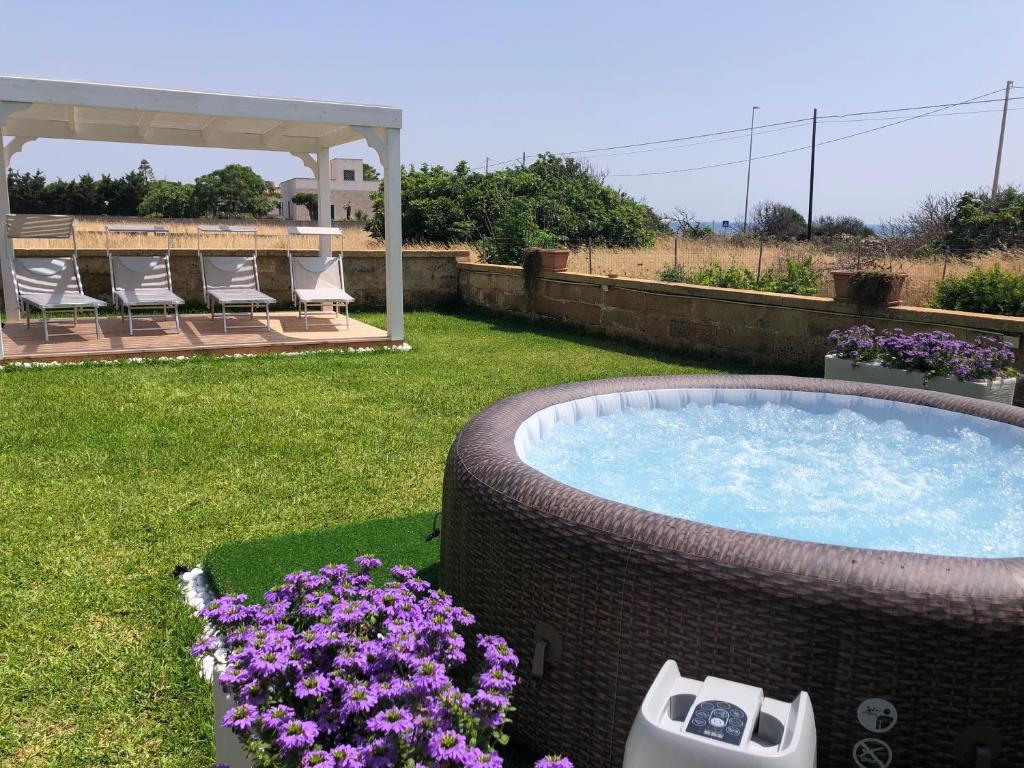 托雷圣乔万尼乌Villa Rosa zona Torre San Giovanni的后院设有热水浴池和紫色鲜花