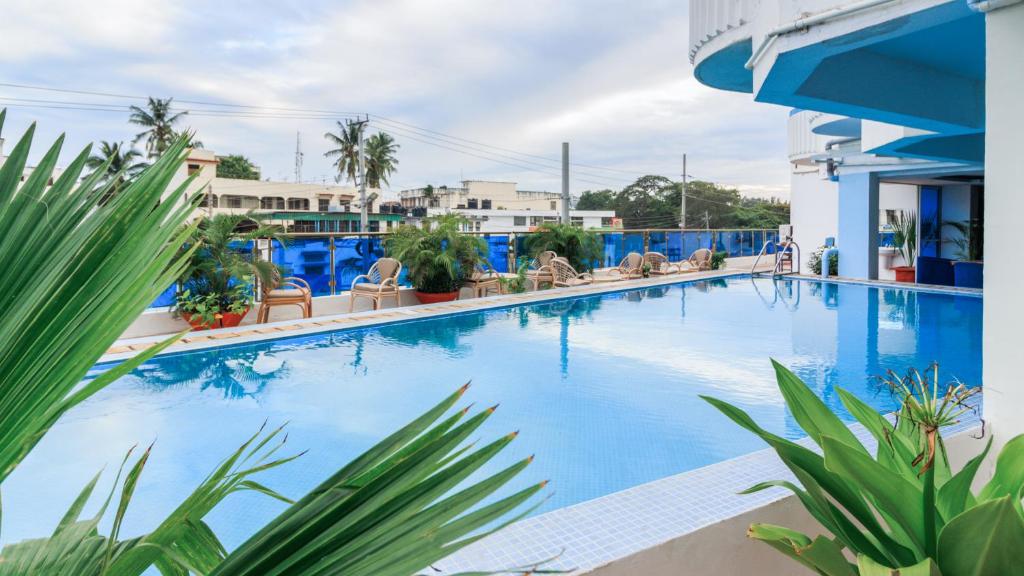 蒙巴萨Hotel Sapphire的一座带椅子和植物的大型蓝色游泳池