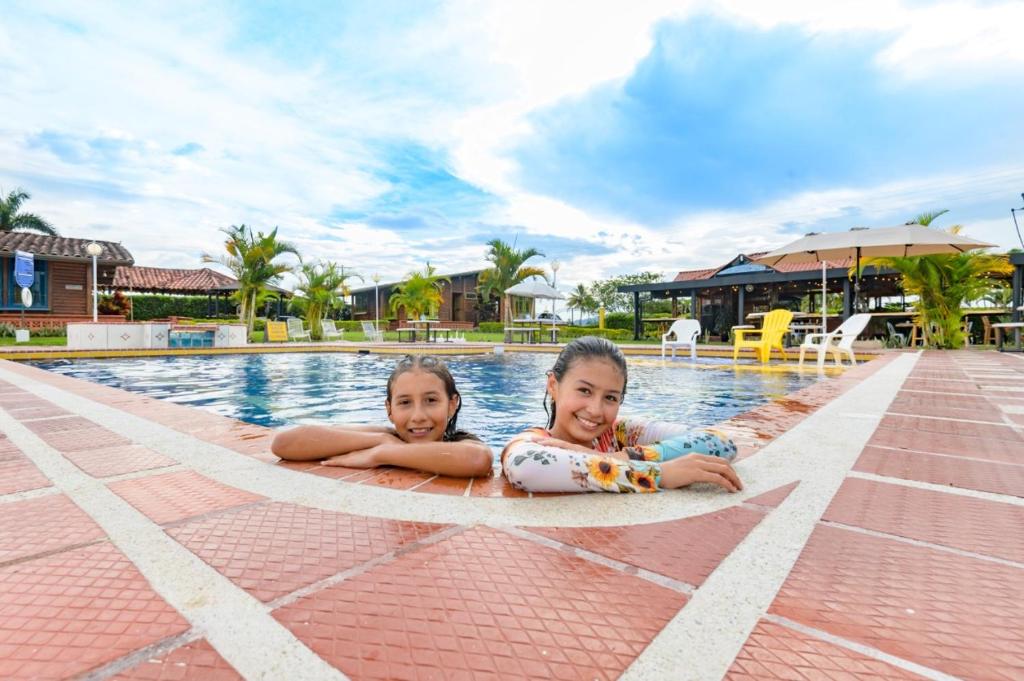 金巴亚Cabitat Cabañas的两个小女孩躺在游泳池边