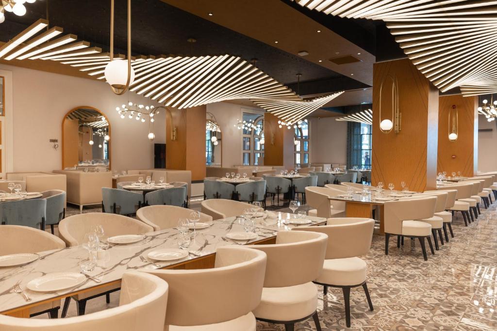 阿拉尼亚Serenity Queen Hotel的用餐室配有桌椅和吊灯。