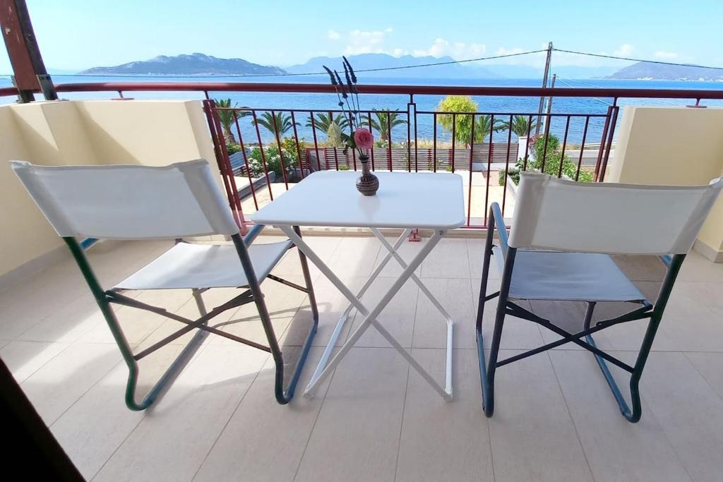 爱琴娜岛A balcony of Aegina by the saronic gulf的阳台上配有一张白色的桌子和两把椅子