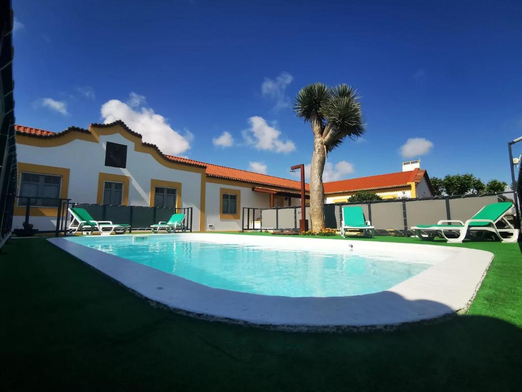 蓬塔德尔加达Quinta São José da Relva的棕榈树屋前的游泳池