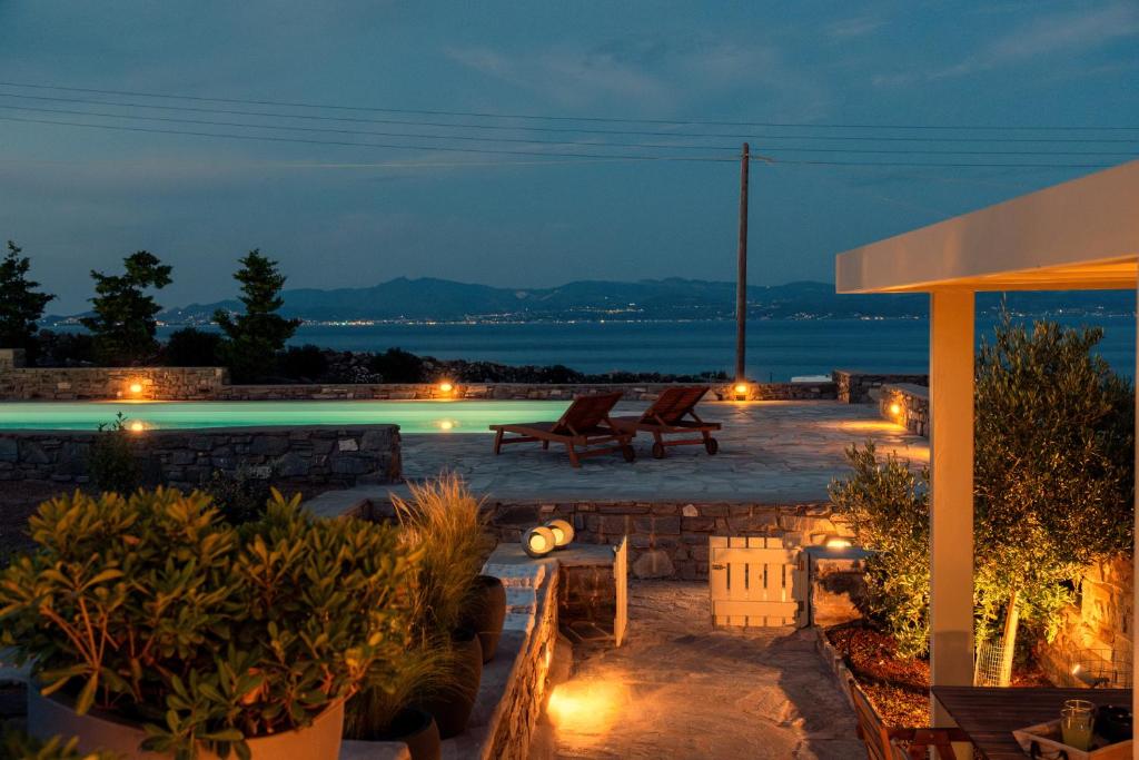 帕罗斯岛Kallirroe Deluxe Villa with Sea View and Pool的一个带椅子的庭院和夜间游泳池