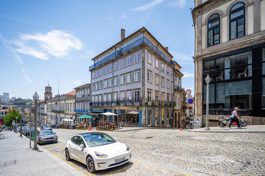 波尔图Casas do Porto - Ribeira Apartments的停在城市街道上的白色汽车,街道上有许多建筑