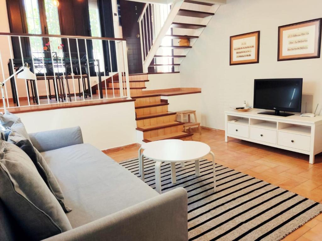 桑卢卡尔-德巴拉梅达PRECIOSO LOFT en PALACIO DE GODOY的带沙发和电视的客厅以及楼梯。
