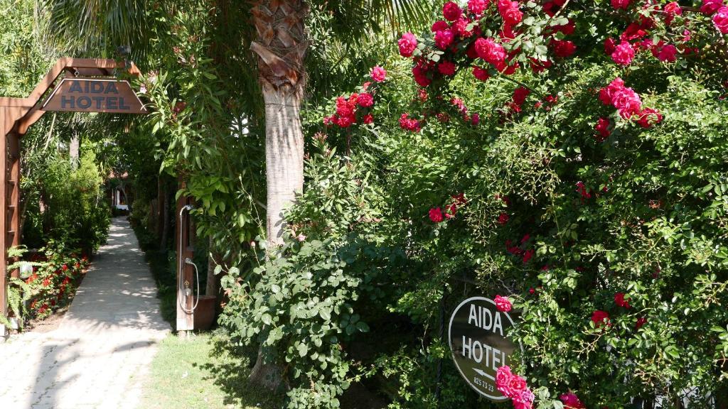 契拉勒爱达酒店的一座花园,花园内有玫瑰和阿尔法酒店标志