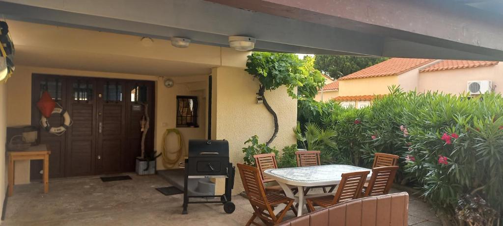 乐巴凯尔斯location maison de vacances jusqu&#39;à 6 personnes près du port et de la plage的带桌椅和烤架的露台